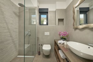A modern bathroom with a glass shower enclosure, a toilet, a large sink, and a mirror with a decorative frame. - Luxury Villa Natali With Pool,terrace and sea View (Podstrana)
