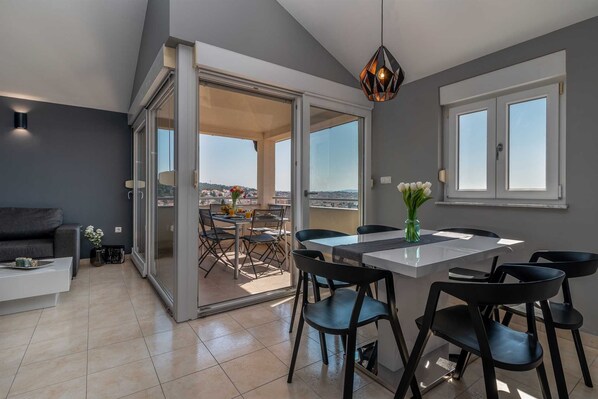A modern living room with a sliding glass door leading to a balcony with a city view.