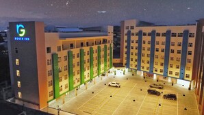 A hotel with a central courtyard, multiple parking spaces, and a prominent building with a logo on the left. - Rogen Inn (Davao)