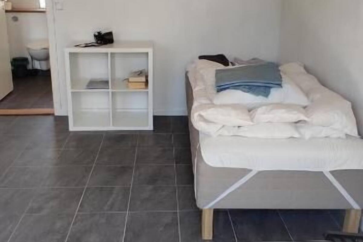 Um quarto com uma cama, um console branco e piso de azulejos.