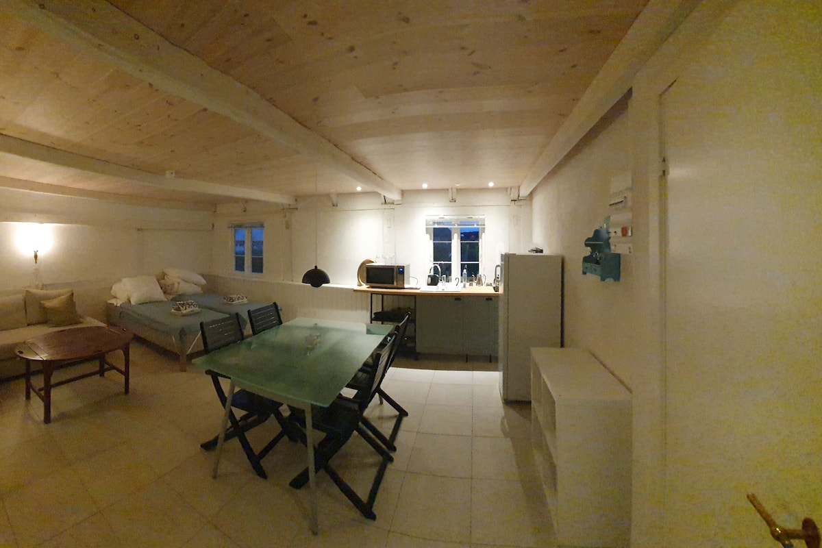 Quarto compacto com sofá, mesa de jantar e cozinha compacta.