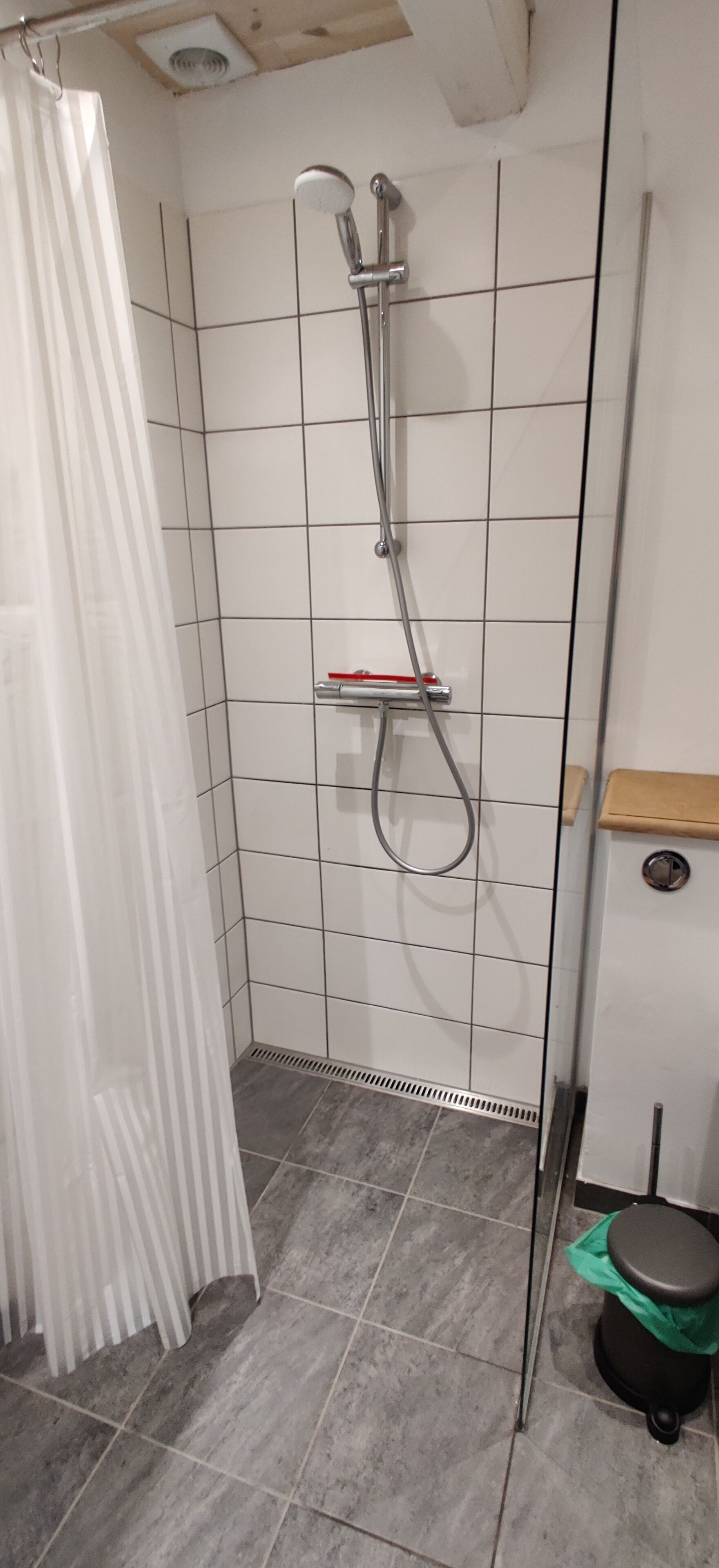 Un área de ducha con pared de azulejos, un cabezal de ducha y un estante.