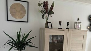 A dining area with a wooden table and chairs, a cabinet with glass doors, a potted plant, and a framed artwork on the wall. - Superb Appartment in Antwerpen (Antwerp)