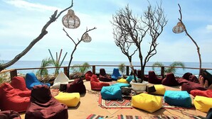 An outdoor seating area with colorful bean bags and hanging wicker lamps, overlooking the sea. - Olea Residence, Luxury sea View Apartment With Private Beach (Himarë)