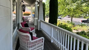 A covered porch with white wicker chairs and a white railing. - Beautiful Home Walking Distance St Helena and Meadowood resort privileges. (St Helena)