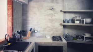A kitchen with a concrete countertop, a gas stove, a sink, and shelves with dishes. - Nut House Apartment Near the sea in a Villa With Garden (Altavilla Milicia)