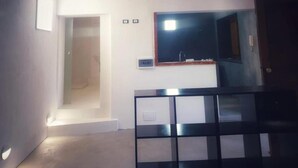 A room with a large mirror, a small sink, and a door leading to another room. - Nut House Apartment Near the sea in a Villa With Garden (Altavilla Milicia)
