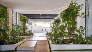 Un couloir intérieur moderne, doté d’un sol en béton, de murs blancs et de plantes vertes disposées dans des jardinières.