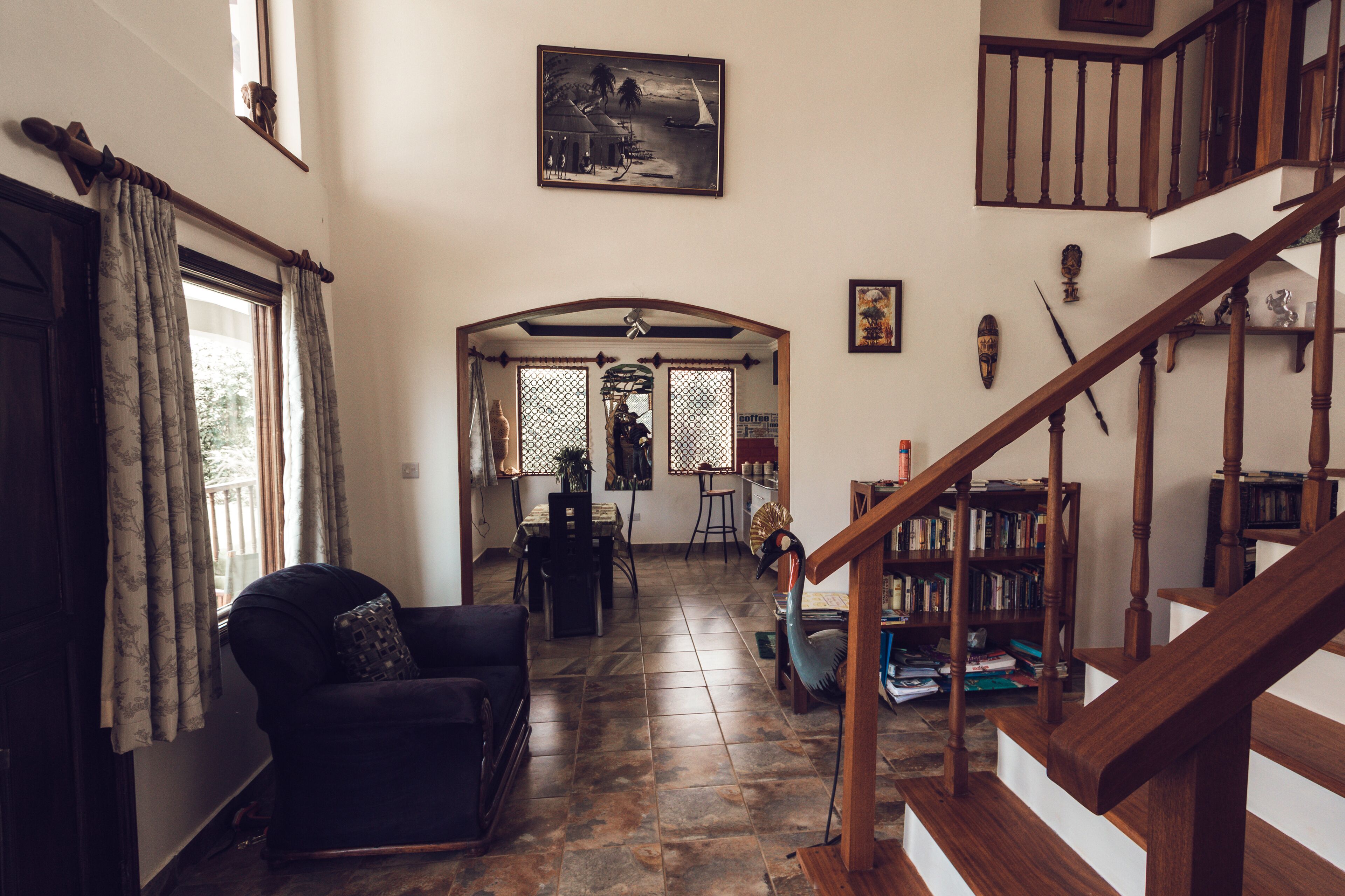 Un salón amplio con escalera de madera, comedor y vistas al exterior.