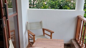 Mesa y sillas de madera en un patio empedrado con vista a la vegetación.