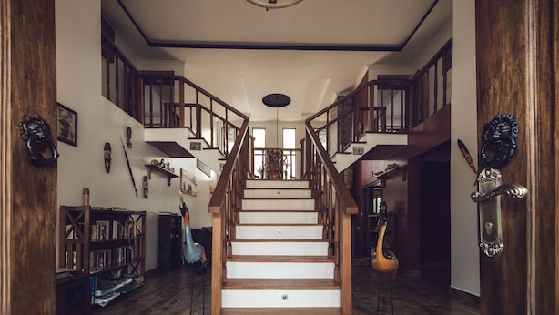 A grand staircase with wooden railings and a chandelier, leading to a second floor with a view of the outdoors. - Room-kilihouse B&b Large Ensuite Double (Kilimambogo)