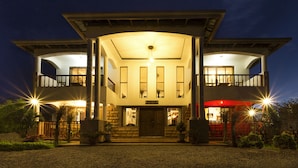 A two-story building with a central entrance, balconies on the upper floor, and a well-lit facade. - Room-kilihouse B&b Large Ensuite Double (Kilimambogo)