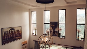 A room with large windows, a painting, a sculpture, and a chandelier. - Room-kilihouse B&b Large Ensuite Double (Kilimambogo)