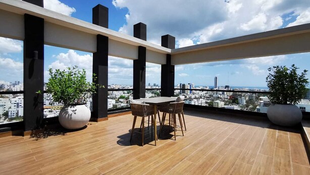 A rooftop terrace with a wooden floor, a table with chairs, and potted plants. - "1 Bedroom Luxury Condo Jacuzzi/gym Mountains View 505" (Santo Domingo)