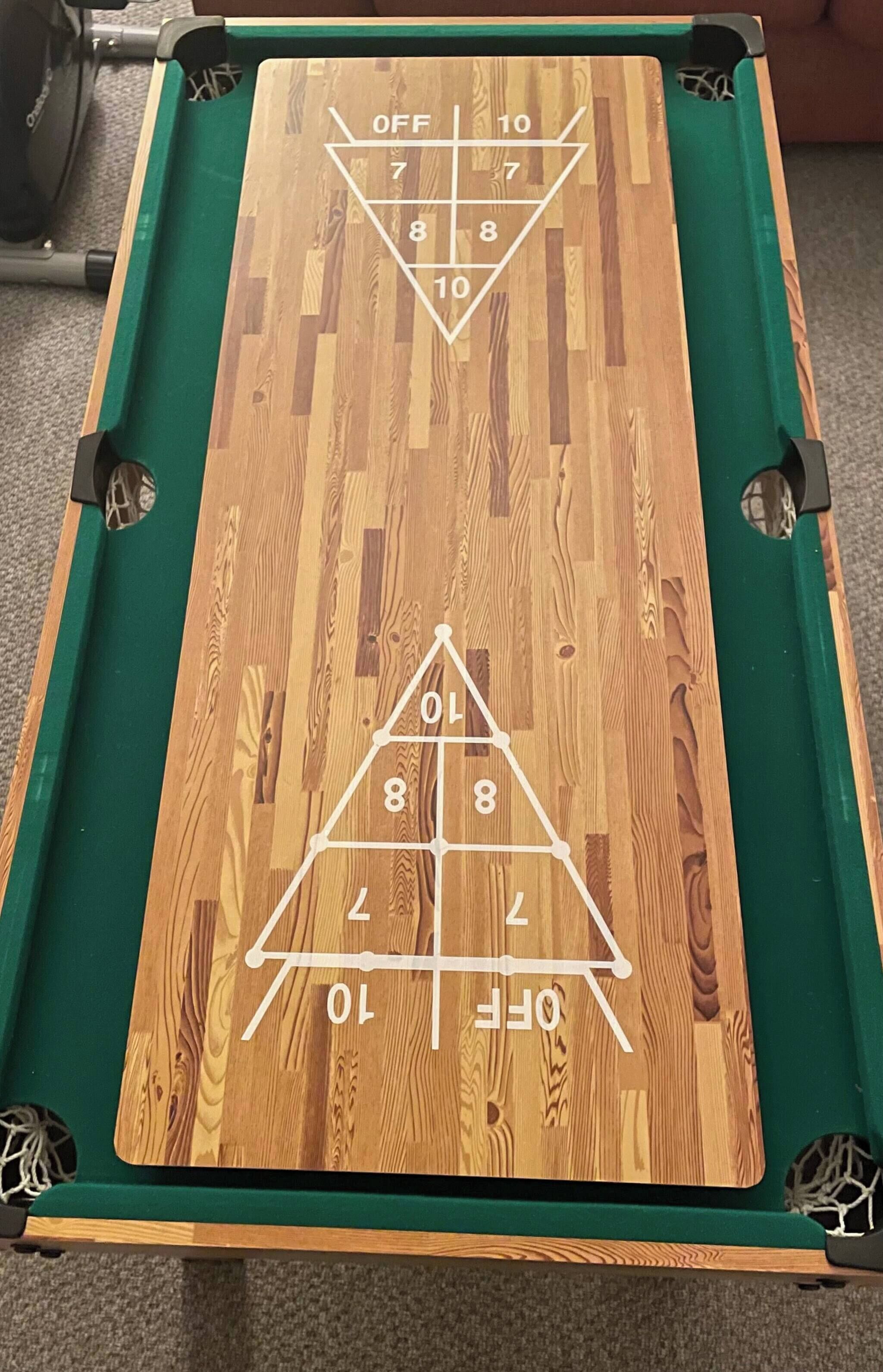 A pool table with a wooden surface and green felt borders.