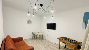A living room with a sofa, a wooden table, a TV, and a ceiling light fixture. - 1 Bedroom Pet Friendly Apt Wd Free Wifi, Parking, Netflix & Pool Table. Sleeps 3 (Kelty)