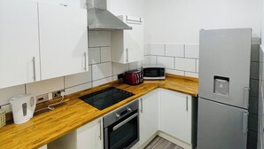 A modern kitchen with white cabinets, a wooden countertop, a stainless steel range hood, a built-in oven, a microwave, and a refrigerator. - 1 Bedroom Pet Friendly Apt Wd Free Wifi, Parking, Netflix & Pool Table. Sleeps 3 (Kelty)