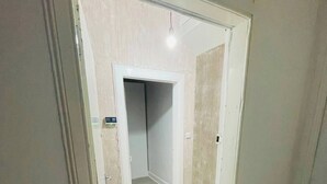 A hallway with a door leading to a room, a light fixture above, and a patterned mat at the entrance. - 1 Bedroom Pet Friendly Apt Wd Free Wifi, Parking, Netflix & Pool Table. Sleeps 3 (Kelty)