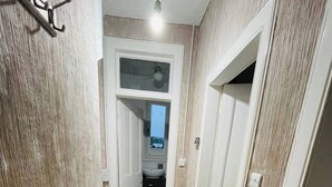 A narrow hallway with a radiator, a door leading to a bathroom, and a ceiling light. - 1 Bedroom Pet Friendly Apt Wd Free Wifi, Parking, Netflix & Pool Table. Sleeps 3 (Kelty)