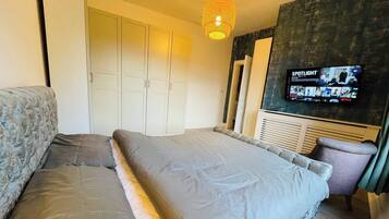 Ein Schlafzimmer mit einem Bett, einem Fernseher, einem Kleiderschrank und einer Pendelleuchte.