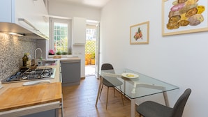 A modern kitchen with a gas stove, wooden countertop, and a glass dining table with chairs. - Amazing Viale Trastevere with Terrace (Roma)