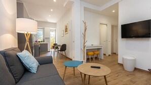 A modern living room with a sofa, a small round table, and a television mounted on the wall. - Amazing Viale Trastevere with Terrace (Roma)