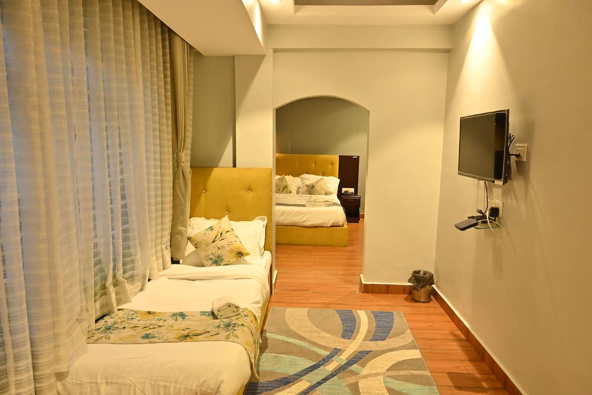 Ein Hotelzimmer mit zwei Betten, einem an der Wand befestigten Fernseher und einer kleinen Mülltonne.