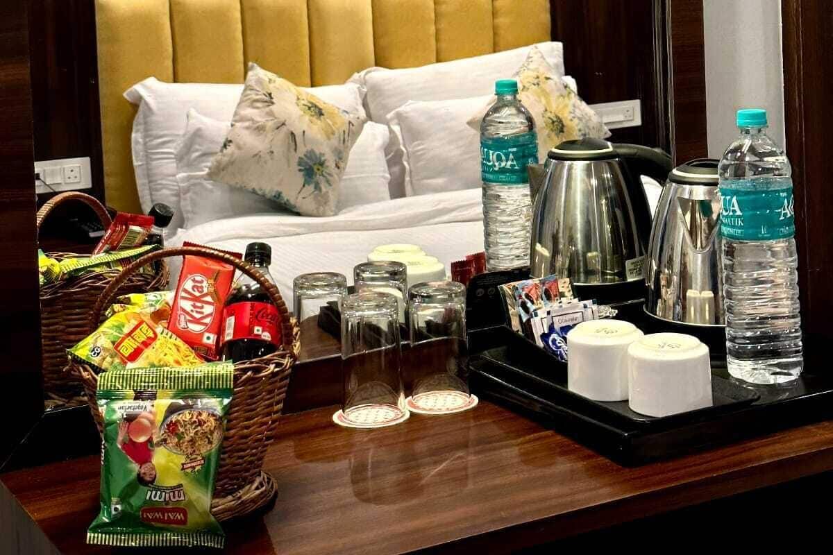 Ein Hotelzimmer mit einem Bett, einem Nachttisch mit Snacks, Wasserflaschen und einem Wasserkocher.