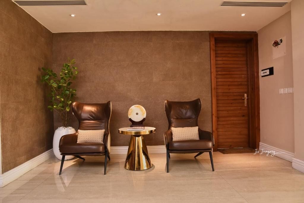 A room with two leather chairs, a small round table, and a potted plant.