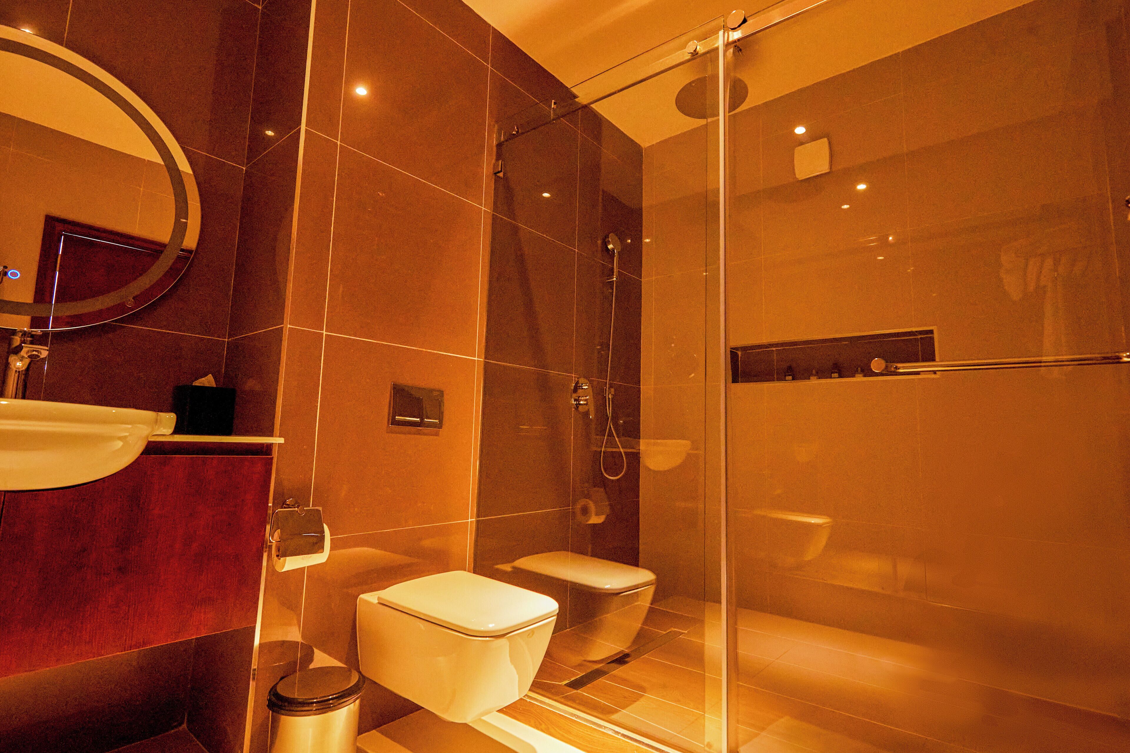 Een moderne badkamer met een douchecabine van glas, een toilet en een wastafel met een spiegel erboven.