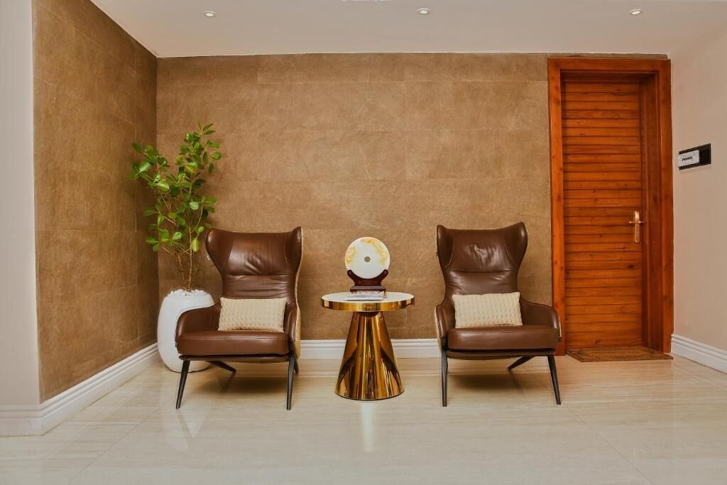 A room with two leather armchairs, a small round table with a decorative item, and a potted plant.