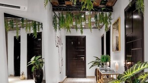 A modern hallway with hanging plants, a wooden door, and a dining area with a table and chairs. - The Yacht Hotel (Lekki)