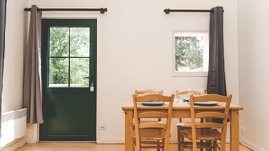 Ruokailutila, jossa on puinen pöytä ja tuolit, vihreät ovet ja ikkuna, jossa on verhot.