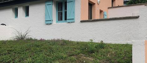 A two-story building with a white facade and teal shutters.