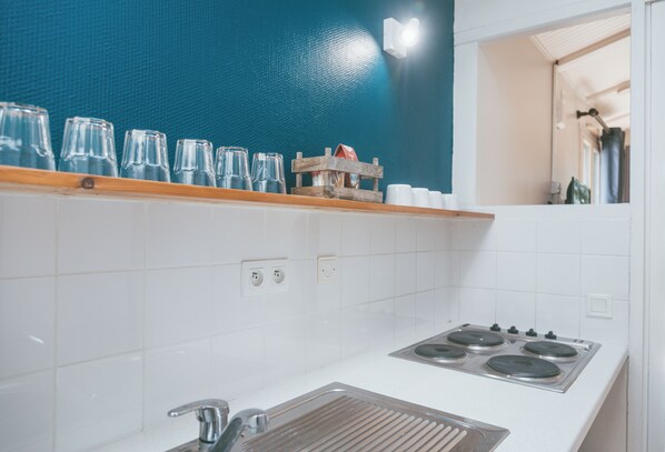 A kitchen with white tiles, a stove, a sink, and a blue wall.