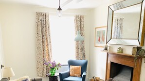 Un salon avec un canapé, un fauteuil, une cheminée et un grand tapis.