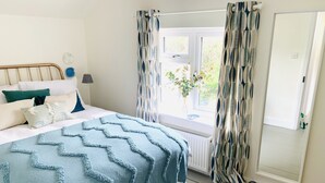 Une chambre à coucher avec un lit, une fenêtre avec des rideaux, un radiateur et une porte.