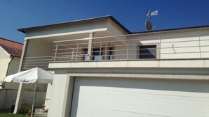 A modern two-story house with a balcony, a garage, and a satellite dish. - Bright, modern house with green views! (Lage)