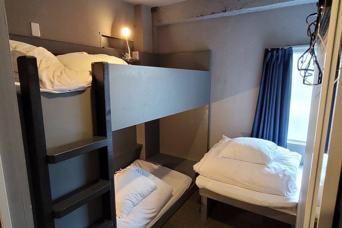 A bunk bed room with a headboard, a bedside table, and a lamp.