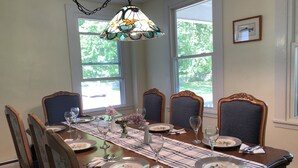 Comedor con una mesa de madera dispuesta para seis personas, rodeada de sillas tapizadas con estampados florales.