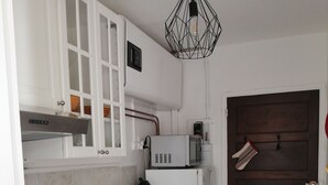 A compact kitchen with a washing machine, a microwave, a coffee maker, and a kettle. - Furnished studio Guéthary (basque coast)30m2-center village and beaches on foot **2023 (Guéthary)