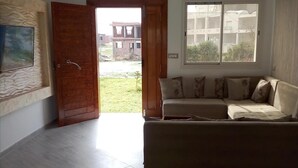 Ein Wohnzimmer mit einer Couch, einer Holztür und einem Fenster.