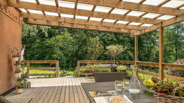 A wooden deck with a table set for dining, surrounded by wooden furniture and potted plants. - Pet friendly home in Videbæk with WiFi (Videbæk)