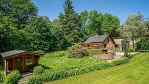 A rustic cabin with a wooden exterior, a small porch, and a well-maintained garden with a circular water feature. - Pet friendly home in Videbæk with WiFi (Videbæk)