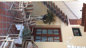 A room with a staircase, wicker furniture, a chandelier, and a door with glass panels. - Virgen Del Cerro Apartments (Salta)