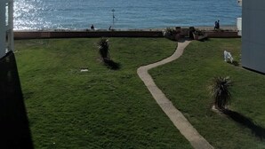Vista di una zona erbosa con un sentiero che conduce a una spiaggia, con vista sul mare.