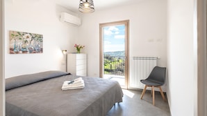 A bedroom with a bed, a dresser, a chair, a radiator, and a window with a view of the countryside. - Nice home in Laureana Cilento with house sea view (Laureana Cilento)