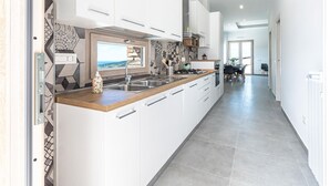 A modern kitchen with white cabinets, a wooden countertop, and a view through the window. - Nice home in Laureana Cilento with house sea view (Laureana Cilento)