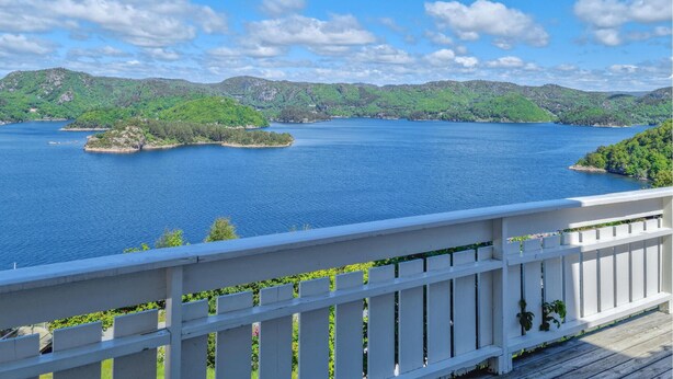 A view of a lake with multiple islands, surrounded by green hills.