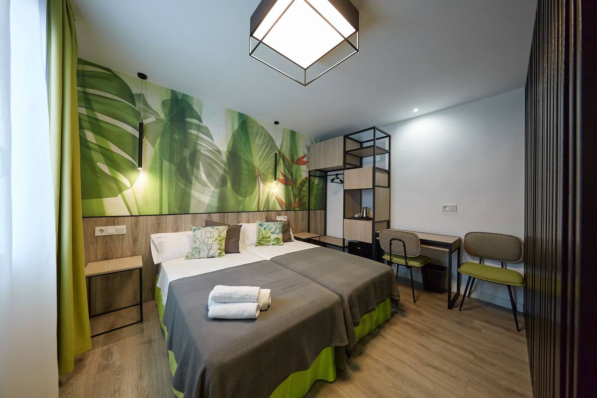 A modern hotel room with a large bed, a desk, and a chair.